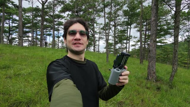 Man holding a drone controller in a pine forest in Da Lat Vietnam
