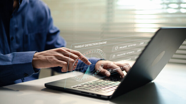 Cybersecurity analyst monitors a threat detection dashboard on a laptop showing malware, phishing and exploit activity. The scene represents cyber defense, threat intelligence and incident response.