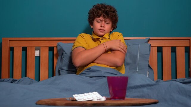 12 year old boy child suffering from a migraine headache &ndash; student experiencing head pain and fatigue stress from homework and studying -  Fever, illness, and medical care medicine in childhood