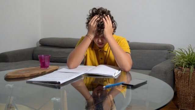 12 year old boy child suffering from a migraine headache &ndash; student experiencing head pain and fatigue stress from homework and studying -  Fever, illness, and medical care in childhood