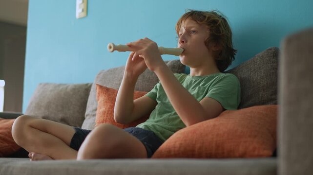 A little boy learns to play the flute at home, practicing with focus and enthusiasm in a cozy, warm setting. A charming scene of early musical exploration, creativity, and childhood growth.