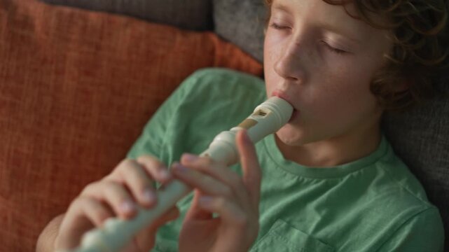A little boy learns to play the flute at home, practicing with focus and enthusiasm in a cozy, warm setting. A charming scene of early musical exploration, creativity, and childhood growth.