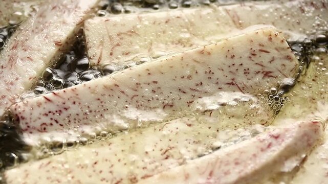 Top view of taro stick fries deep frying in boiling hot oil.