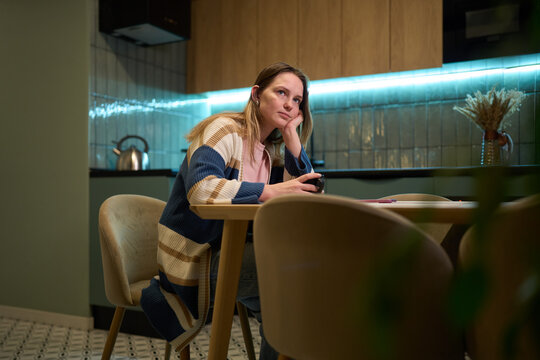 Woman taking a sip of hot drink at cozy kitchen table