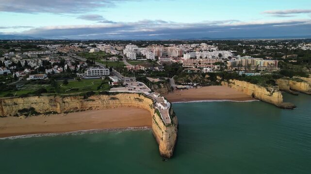 Aerial view of Chapel Nossa Senhora da Rocha on a cliff overlooking the beach and coastal town in Porches, Faro, Portugal.