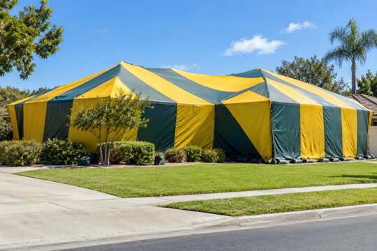 House covered by striped fumigation tent on sunny residential street - termite tenting and pest control service