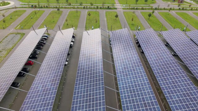 Aerial view of Zonneweide solar parking lot with rows of photovoltaic panels over parked cars, surrounded by green lawns and pathways in Harderwijk, Gelderland, Netherlands.