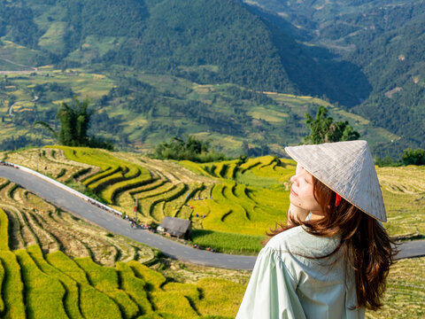 Woman in conical hat gazing over terraced fields with hair in the wind, Y Ty, Lao Cai, Vietnam