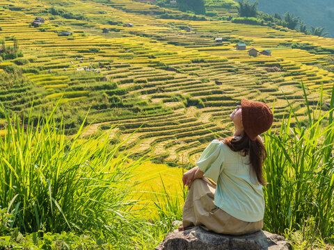 Woman gazing skyward while sitting above sprawling rice terraces, Y Ty, Lao Cai, Vietnam