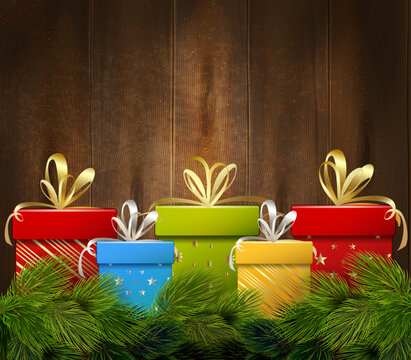 Christmas gift boxes with golden ribbons on rustic dark wood background with pine branches