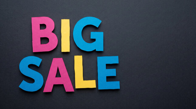 Colorful paper letters spell "BIG SALE" on a dark background, symbolizing retail promotion and shopping opportunities with ample free space