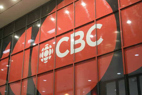 large sign on the exterior facade of Canadian Broadcasting Corporation, a media company, located at 250 Front St W, Toronto - night