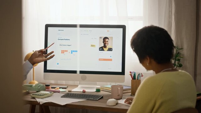 African American male tutor explaining online lesson on computer to African American teenage girl, rear view. Clip fits private tutoring services, digital education apps, STEM marketing