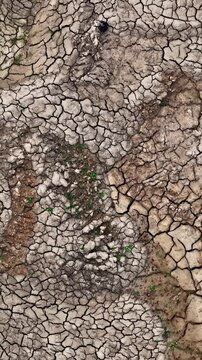 Aerial view of cracked dry earth at Tagebau Hambach with sparse green vegetation in Elsdorf, Nordrhein-Westfalen, Germany.