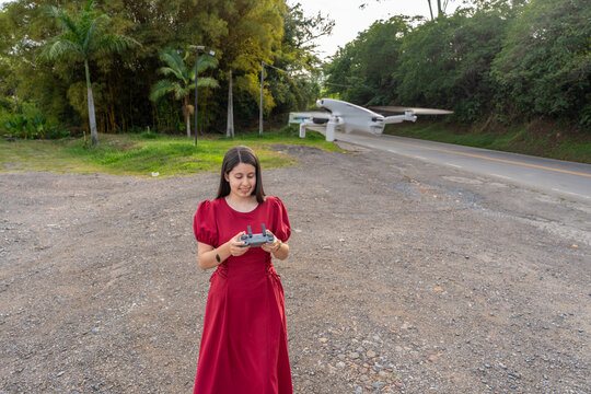 Young Woman Operating Modern Camera Drone Outdoors Near Countryside Road