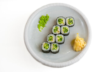 Cucumber maki sushi rolls with wasabi and pickled ginger on white plate, top view, isolated on white background © Evghenii Blanaru