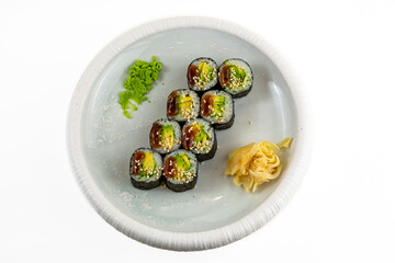 Avocado maki sushi rolls with unagi sauce and sesame, wasabi and pickled ginger on white plate, top view, white background © Evghenii Blanaru