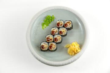 Eel maki sushi rolls with unagi sauce and sesame, wasabi and pickled ginger on white plate, top view, white background © Evghenii Blanaru