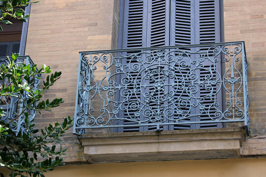 Balcon classique en fer forg&eacute; ornemental avec volets persiennes en bois et fa&ccedil;ade en briques