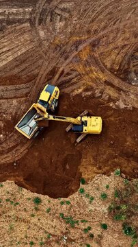 Aerial view of yellow excavator and dump truck working in the brown earth of the Tagebau Hambach open pit mine in Elsdorf, Nordrhein-Westfalen, Germany.