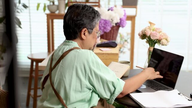 Senior woman, florist small business owner, digital skill, manages inventory on laptop, confident with technology in retail operations, bookkeeping tasks, remote access to financial control and supply
