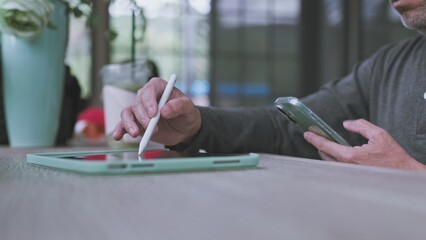 Remote worker handles digital design tasks, managing design projects on tablet screen while design drafts sync smoothly across mobile devices. © Mdisk