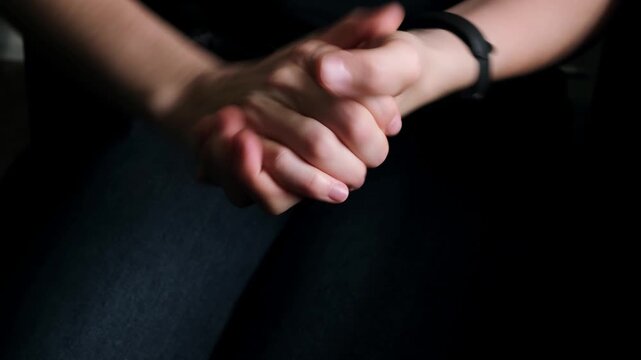 A person rubbing his hands against a dark background indoors, body gesture, waiting mood, communication sign. Warm up your hands. Skin friction. High quality 4k footage.