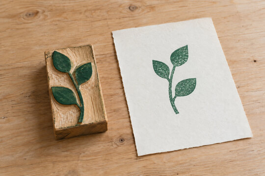 Wooden botanical printing block beside a green leaf print on cotton paper
