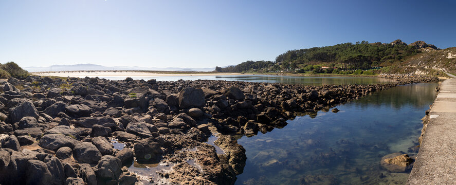 panoramic view of the lake and rocky walkway at cies islands natural park in galicia spain