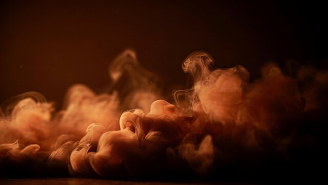 Dynamic orange and brown smoke plumes gracefully rising on a mysterious dark background