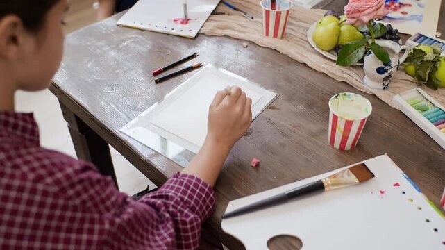 Girl painting still life with brush during creative master class in art studio. Ideal for art school promotion, educational commercials, and creative hobby advertising