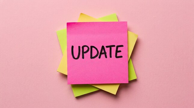 Pink sticky note with update text on top of colorful sticky notes stack with displays word update update atop communication notification organization arrangement handwritten information bright