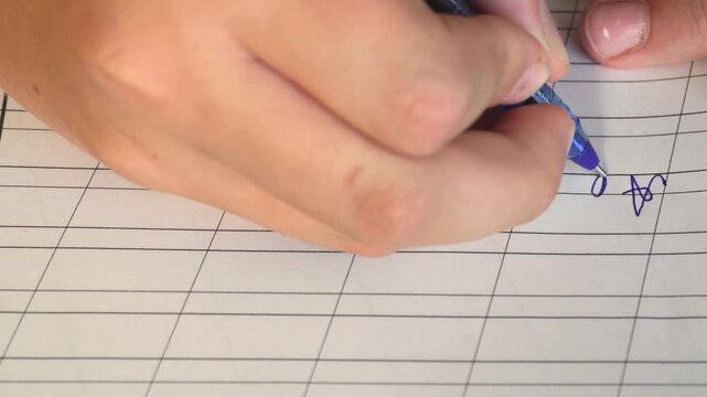 Close-up of a hand writing with a blue pen on grid paper. Hand-drawn star symbol, studying, note-taking, education, homework concept.