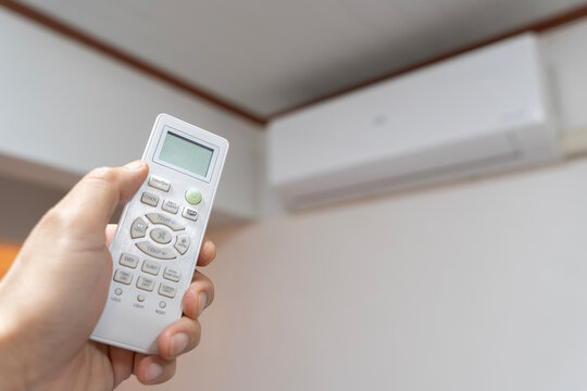 Person uses remote to operate air conditioning system in indoor space