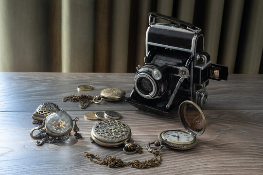 vintage camera and vintage pocket clock with glass lid on wooden background