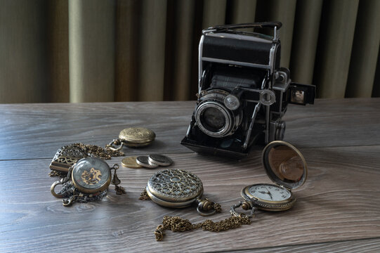 old camera and vintage pocket clock with glass lid on wooden background