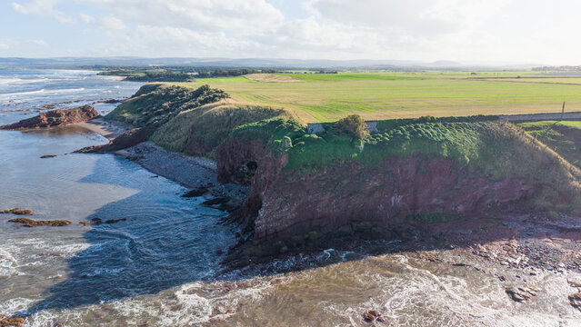 Ruins of historic Seacliff Tower standing on high red sandstone cliffs along coast in East Lothian Scotland