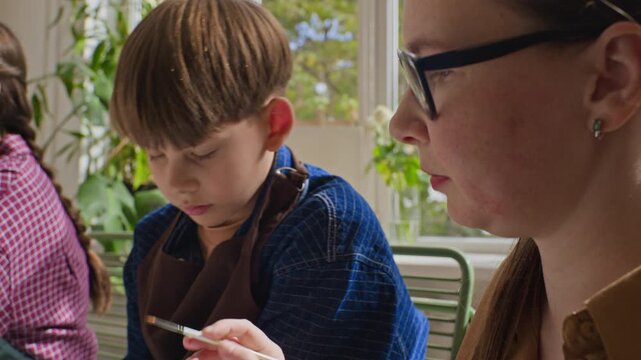 Children painting still life with teacher assistance during art masterclass. Footage suited for promoting creative kids education, watercolor workshops and school programs