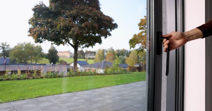 Man opening large aluminum sliding glass door to a home backyard garden terrace