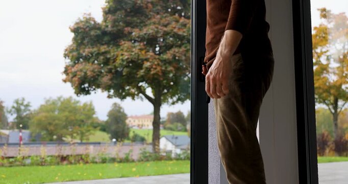 Man opening large aluminum sliding glass patio door to a backyard garden