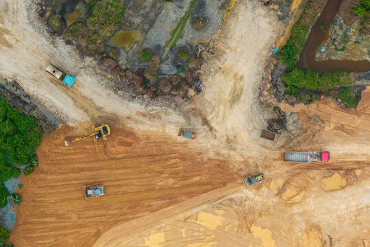 Aerial view of a construction site with heavy machinery including excavators and dump trucks working on earthworks in Simpang Ampat, Penang, Malaysia.