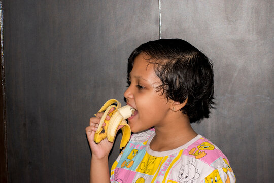 Portrait of child eating healthy fruit banana, nutritious food choices, childhood nutrition and an active healthy lifestyle.