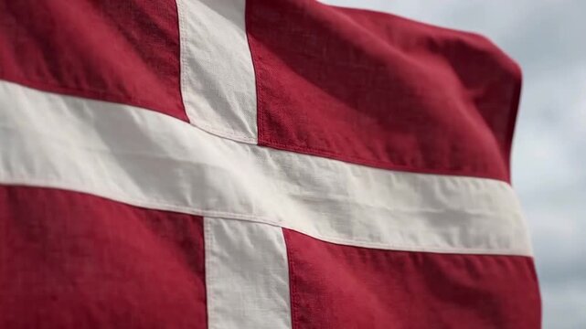 Danish flag waving in the wind against a cloudy sky