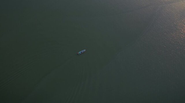 Fishing boat stationary on calm Pueblo Viejo lagoon with sunlight reflecting on water aerial drone orbit shot over small wooden vessel near Tampico Ciudad Cuauhtemoc Veracruz Mexico