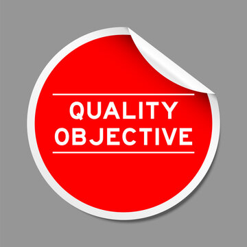 Red color peel sticker label with word quality objective on gray background