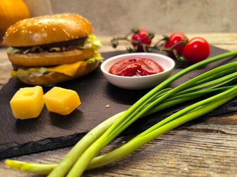greens, cheese, tomatoes with hamburger on a rustic board