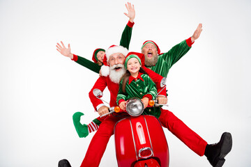 Fototapeta premium Santa and two elves riding a red scooter with a smiling child, laughing and celebrating Christmas holiday spirit and family fun