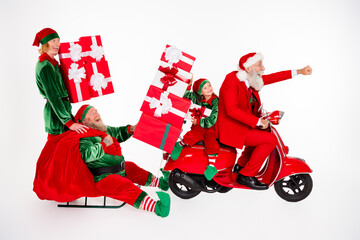 Fototapeta premium Santa Claus and cheerful elves delivering oversized wrapped gifts on a red scooter and sled in a playful Christmas holiday celebration