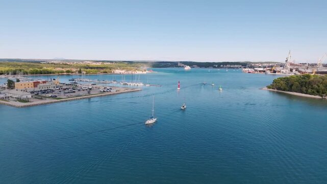 Aerial view of Marina Polesana Pula with sailing boats in the harbor and industrial shipyard in the background in Pula, Istarska zupanija, Croatia.