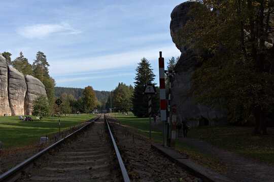 Railway track leading past sandstone rock towers in Adrspach on a sunny autumn day, Czech Republic